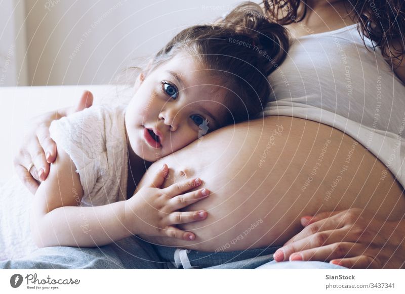 Glückliches Mädchen umarmt den Bauch der schwangeren Mutter Kind Frau Schwangerschaft Mama Familie weiß Baby wenig Liebe Lügen jung Bett Schlafzimmer