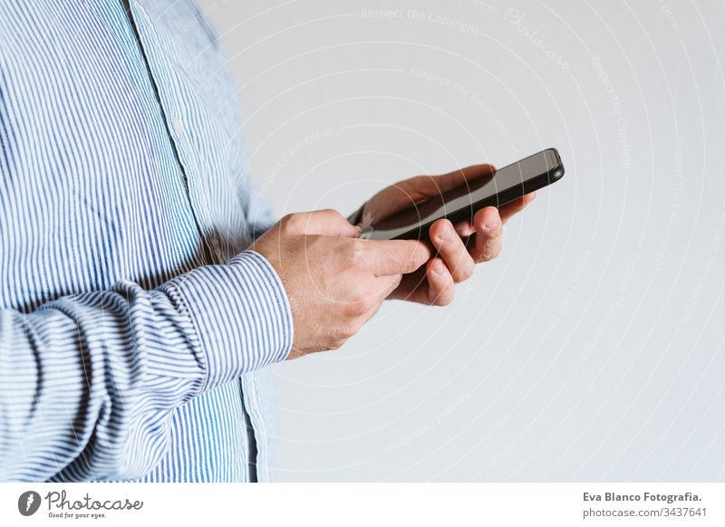 Nahaufnahme eines Mannes, der in einem Gebäude ein Mobiltelefon benutzt. Technologie-Konzept Handy unkenntlich Technik & Technologie abschließen Drahtlos Hemd