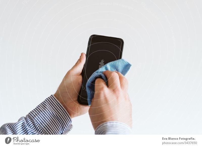 Nahaufnahme eines Mannes, der sein Mobiltelefon mit Desinfektionsmittel reinigt. Hygiene- und Coronavirus covid-19-Konzept Sauberkeit Handy Corona-Virus