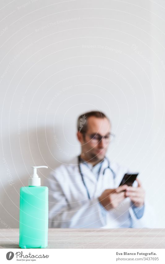 Der Arzt, der ein Mobiltelefon benutzt. Im Vordergrund steht ein Alkohol-Gel oder ein antibakterielles Desinfektionsmittel. Hygiene- und Coronavirus-Konzept. Covid-19