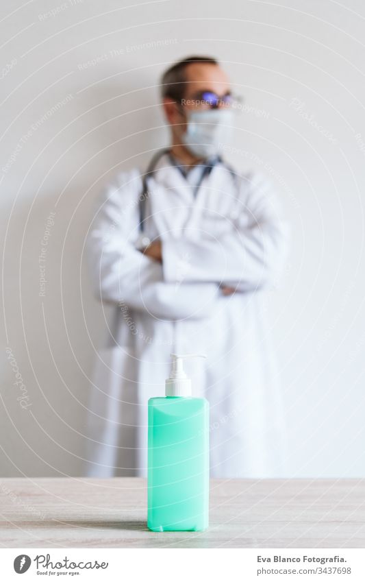Ein Arzt, der im Haus eine Schutzmaske und Handschuhe trägt. Er hält ein Alkoholgel oder ein antibakterielles Desinfektionsmittel in der Hand. Hygiene- und Coronavirus-Konzept. Covid-19