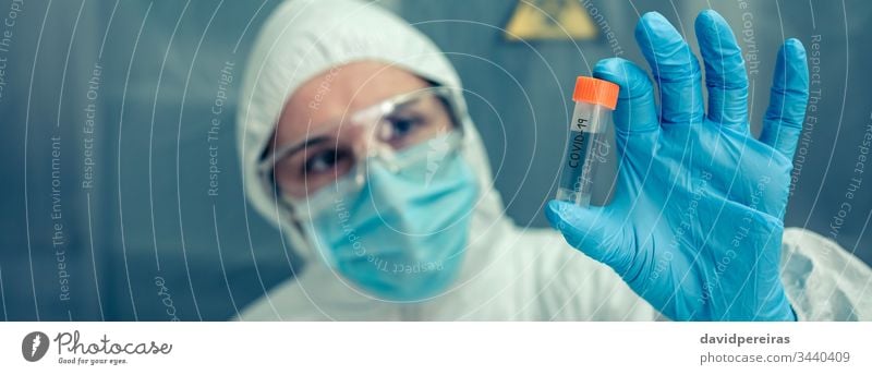 Wissenschaftlerin mit Schutzanzug sieht Fläschchen im Labor Untersuchen Flasche Impfstoff Ampulle Virus Coronavirus Erkundung Transparente Netz Kopfball
