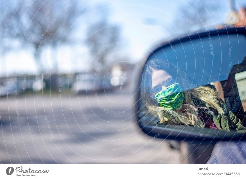 junge Frau mit Mundschutz sitzt im Auto Maske Rückspiegel Spiegel nachdenklich fahren Atemschutzmaske Pkw Schutzmaske Stadt Virus Coronavirus besorgt Viren