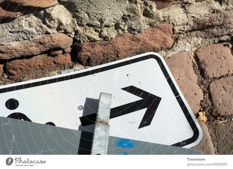 Schilder | weg damit Verkehrsschild abgelegt Schilder & Markierungen Verkehrszeichen liegend Piktogramm Boden Pflastersteine Mauer Sandstein Menschenleer Licht