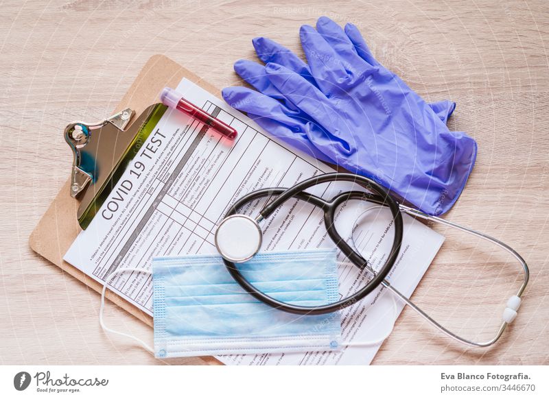 Draufsicht auf einen Arztarbeitsplatz mit Schutzhandschuhen, Schutzmaske, Stethoskop, Blutschlauch und Coronavirus-Test. Covid-19-Konzept Prüfung Corona-Virus