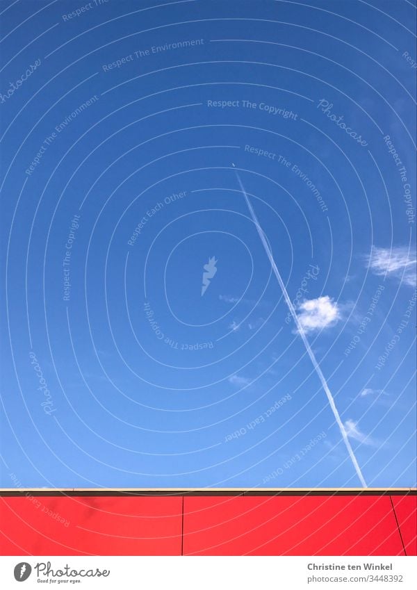 blauer Himmel mit wenigen Wolken, einem Flugzeug mit Kondensstreifen und roter Fassade Blauer Himmel Schönes Wetter Luft Freiheit Luftverkehr Gebäudefassade