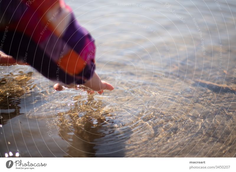 Kind spielt mit Wasser kind mädchen wasser wellen hand entdecken neugierde neugierig spielerisch lernen kalt käälte frühling gewässer kindheit unbeschwert
