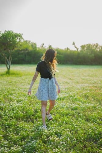 Eine junge Frau geht auf einem Feld mit kleinen Blumen 2017-2020 erste Einfuhr Junge Frau Mädchen elegant Freigeist Jugendliche Mensch feminin Stil schön