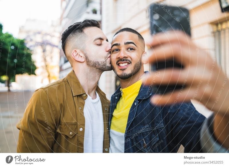 Ein schwules Paar, das sich auf der Straße vergnügt. Liebe Partnerschaft Handy Termin & Datum lieblich positiv Großstadt Freiheit Leben jung Stolz Selfie