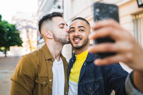 Ein schwules Paar, das sich auf der Straße vergnügt. Liebe Partnerschaft Handy Termin & Datum lieblich positiv Großstadt Freiheit Leben jung Stolz Selfie