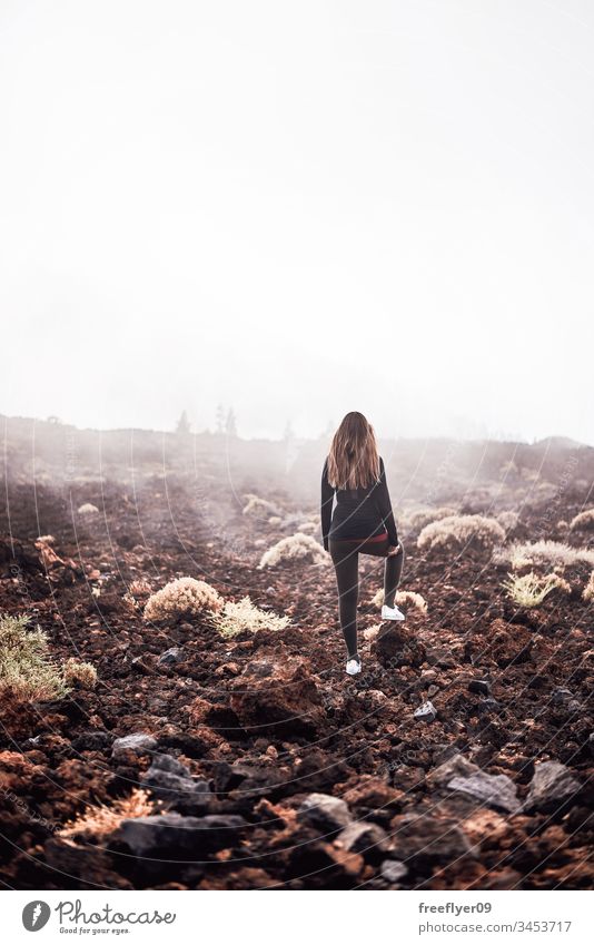 Junge Frau betrachtet den Nebel auf dem Weg zum Teide-Gipfel in Teneriffa, Spanien Erwachsener verbrannt Kaukasier Kleidung wolkig kalt betrachtend
