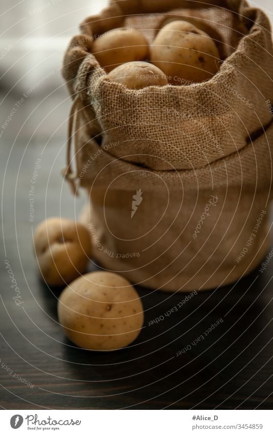 Kartoffeln in Sackleinen auf rustikalem Holzgrund Hintergrund Tasche braun Sack mit Sackleinwand Nahaufnahme kulinarisch Diät Erde erdig fallend Lebensmittel