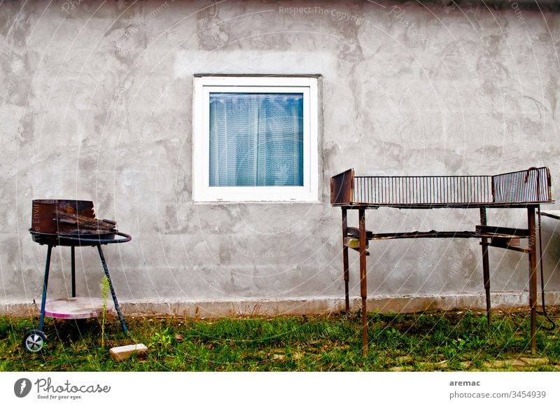 Grill vor einer Wand mit Fenster in einer Erntehelfer Unterkunft grau Gebäude Haus Tristesse Fassade Außenaufnahme Menschenleer Tag Mauer trist
