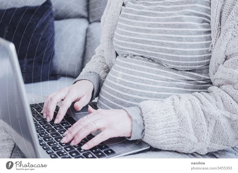 Junge schwangere Frau arbeitet zu Hause mit ihrem Laptop Bauch Computer Arbeit heimwärts Quarantäne Schwangerschaft Mutterschaft arbeiten WiFi Verlauf