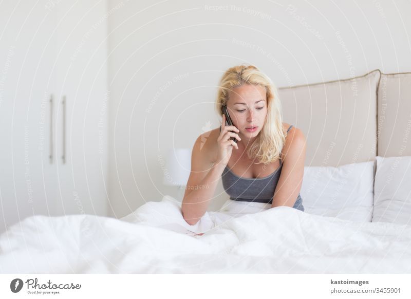 Frau, die morgens im Bett telefoniert. Telefon Anruf Morgen Schlafzimmer reden jung Person Mobile weiß benutzend Kissen Nachrichten heimwärts Raum hören