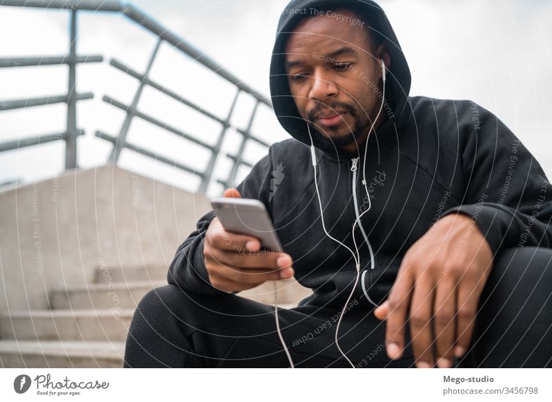 Sportler, der sein Mobiltelefon benutzt. Mann Läufer hören Kopfhörer Training Übung Lifestyle Erwachsener Gesundheit im Freien sportlich Typ laufen Mitteilung