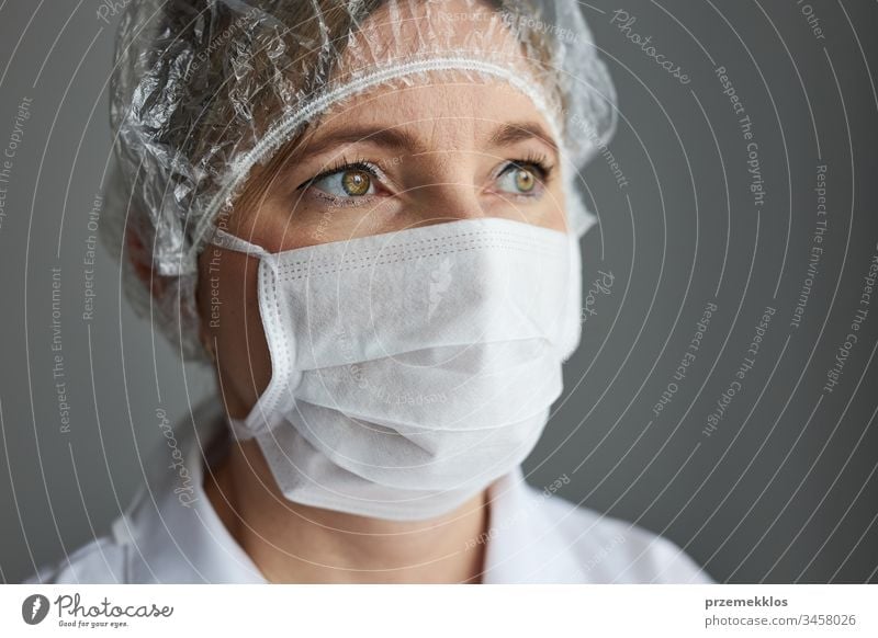 Arzt mit maskiertem Gesicht. Porträt einer jungen Frau, die Uniform, Mütze und Maske trägt, um eine Virusinfektion zu vermeiden und die Verbreitung von Krankheiten zu verhindern. Echte Menschen, authentische Situationen