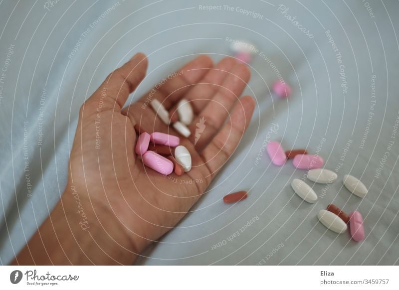 Eine Hand in der mehrere verschiedene bunte Tabletten liegen; Suchtprobleme, Medikamentenmissbrauch, Suizid Pillen Drogen Abhängigkeit Gesundheitswesen