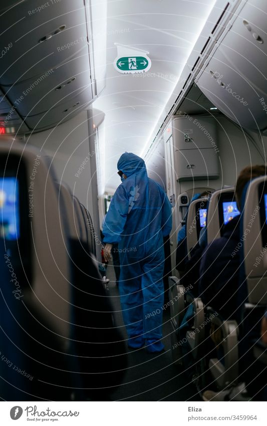 Ein Flugbegleiter in Schutzbekleidung in einem Flugzeug auf einem Rückholflug für gestrandete Reisende während der Corona Pandemie Stewardess geschützt