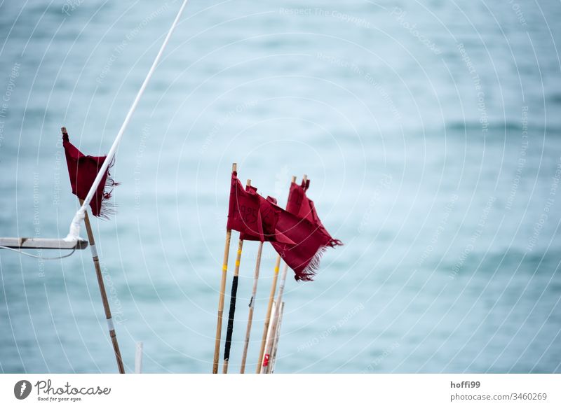 rote Fahnen im Wind auf Fischerboot Rote Fahne Fahnenmast maritim wild windig Meer auf see wehen Himmel flattern blau Sommer
