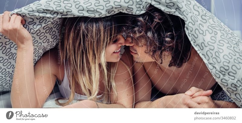 Glückliches junges Paar in der Liebe küsst sich unter dem Bettbezug. Kuss Deckung Bettdecke Federbett Lügen unten Transparente panoramisch Panorama Netz