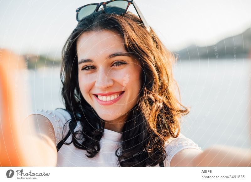 Glückliche schöne junge Frau, die im Sommer am Meer ein Selfie macht MEER Porträt Selbstportrait zahnfarben heiter Gesicht Freude abschließen Mädchen Feiertag