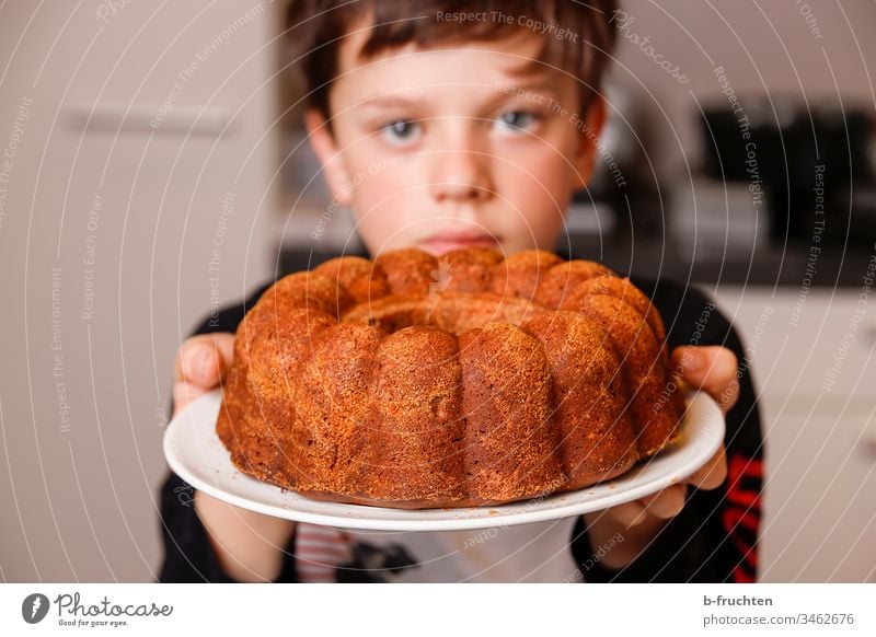 Kind hält Teller mit Kuchen Gugelhupf süß Farbfoto lecker Innenaufnahme Backwaren Süßwaren Dessert halten frisch gebacken zeigen stolz Küche helfen Junge Hand