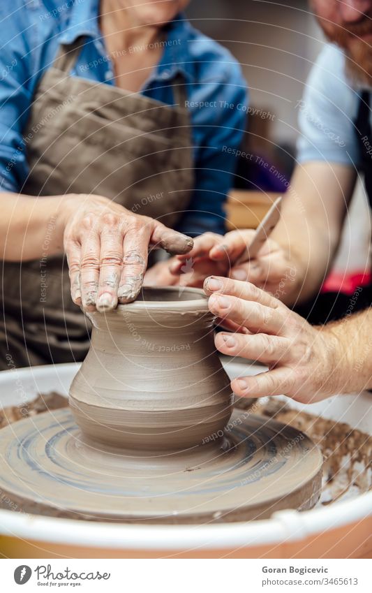 Ältere Frau dreht Ton auf einer Drehscheibe mit einem Lehrer im Töpferkurs Dame spinnen Belehrung Ausbilderin lernen Form Finger Topf drehen. Keramik gekonnt