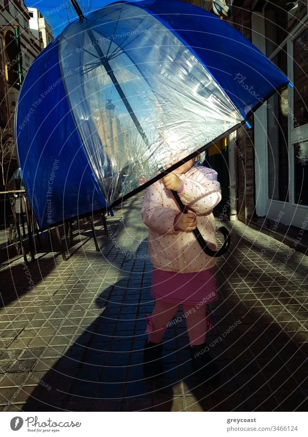 Kleines Mädchen mit großem Regenschirm gegen die Sonne auf der Straße. Kind liebt es, unter zu verstecken Tierhaut Kleinkind Herbst außerhalb fallen Dame