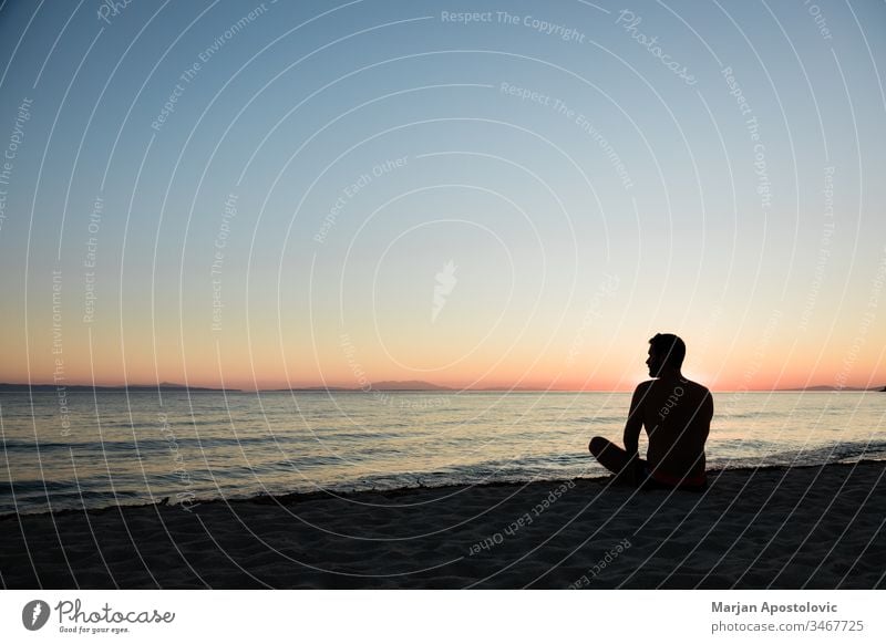 Junger Mann genießt Sonnenuntergang am Strand Erwachsener Abenteuer allein schön Windstille Küste Morgendämmerung Abenddämmerung genießend Freiheit Harmonie