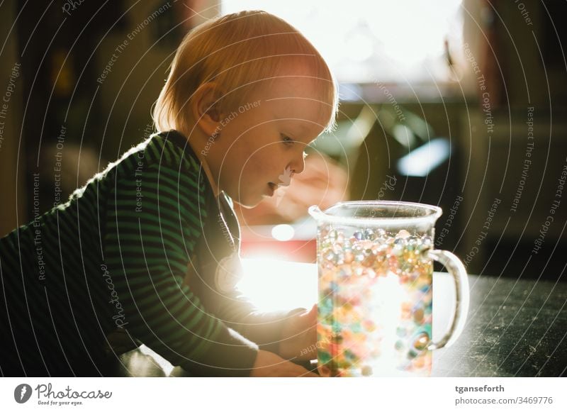 kleiner Junge entdeckt bunte Perlen Farbfoto Kind Porträt perlen Lichteffekt entdecken lernen erforschen Begeisterung Spielen Kindererziehung Kindheit Freude