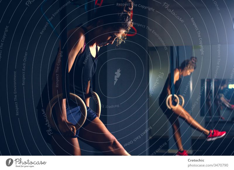 Frau, die mit Anstrengungsausdruck mit rhythmischen Gymnastikringen in einer Turnhalle trainiert Ausdruck anstrengen müde Training künstlerisch Ringe Körper