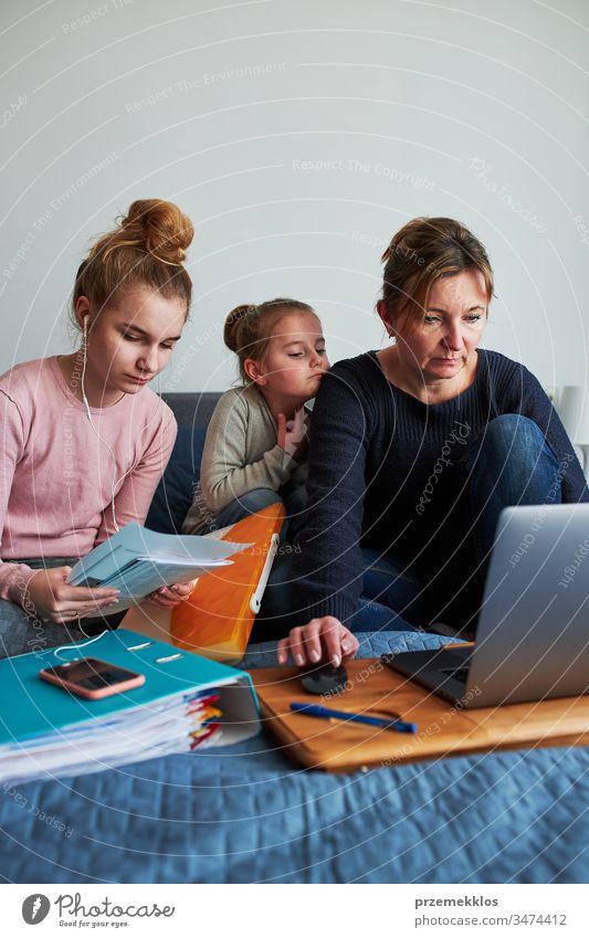 Mutter und Tochter von Frauen, die während der COVID-19-Quarantäne aus der Ferne lernen, indem sie während der Video-Chat-Call-Stream-Online-Kurs Webinar-Lektionen auf einem Laptop von zu Hause aus erledigen. Frauen sitzen im Bett vor dem Computer und schauen auf den Bildschirm