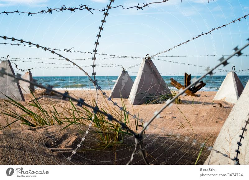Stacheldraht und Beton-Militärzaun am Strand nahe dem Meer auf der Krim Russland Ukraine Annektierung Armee Verbot mit Stacheln versehen Barriere blau Borte