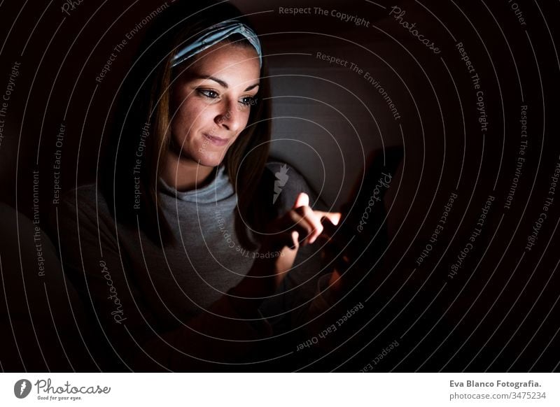 junge Frau zu Hause, die ein Mobiltelefon benutzt. Nachtzeit Handy heimwärts Bildschirm dunkel sich[Akk] entspannen Technik & Technologie Lifestyle Freizeit