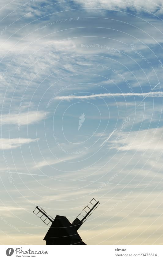 Bockwindmühle am unteren Bildrand in Scherenschnittform und Himmel mit Kondensstreifen Windmühle Holz Schönwetterwolke Flügel Romantik Windmühlenflügel
