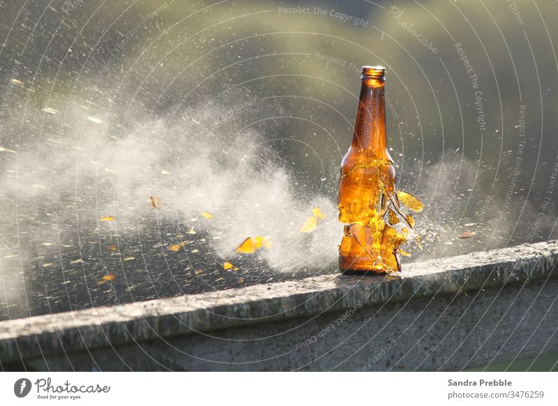 Eine Bierflasche wird zerschossen, und die Glasscherben beginnen zu zersplittern, während der Rauch entweicht braune Flasche Eingefrorene Aktion Glassplitter