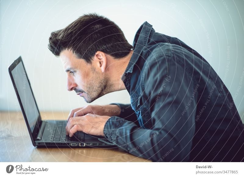 Mann arbeitet konzentriert am Laptop haltungsschäden rückenschmerzen ungesund Körperhaltung Arbeitsplatz laptop arbeiten Büro Schreibtisch Tisch Business