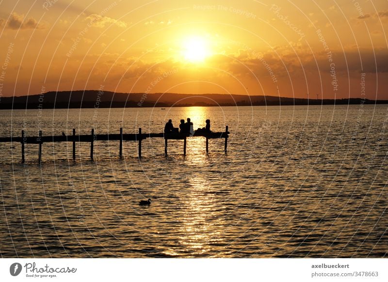 Sonnenuntergang über dem Steinhuder Meer See Silhouette Menschen Steg Menschengruppe Urlaub Erholung Pier Anlegestelle Freunde unkenntlich Sitzen Abend