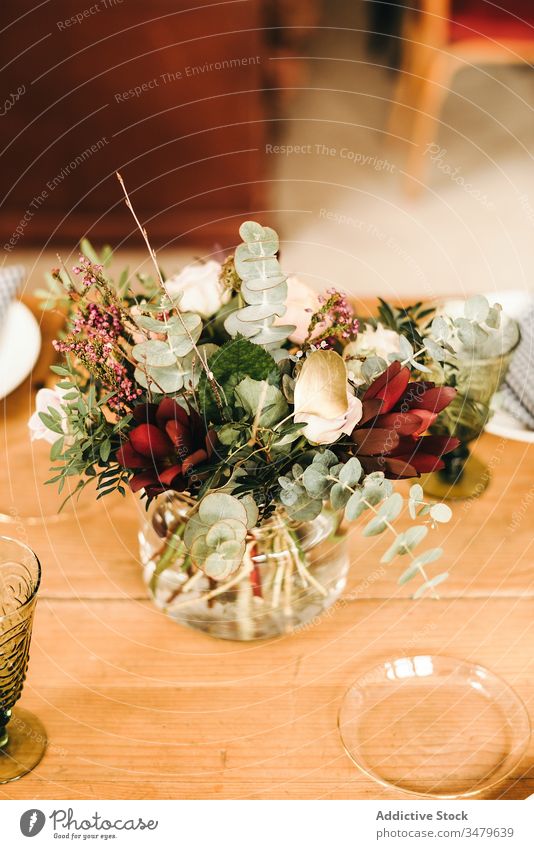 Blumen und Pflanzenzweige auf einer Vase, die einen Holztisch schmückt Haufen Blatt Blumenstrauß Wasser Blütenblatt Konzept Glas frisch Blütezeit Innenbereich