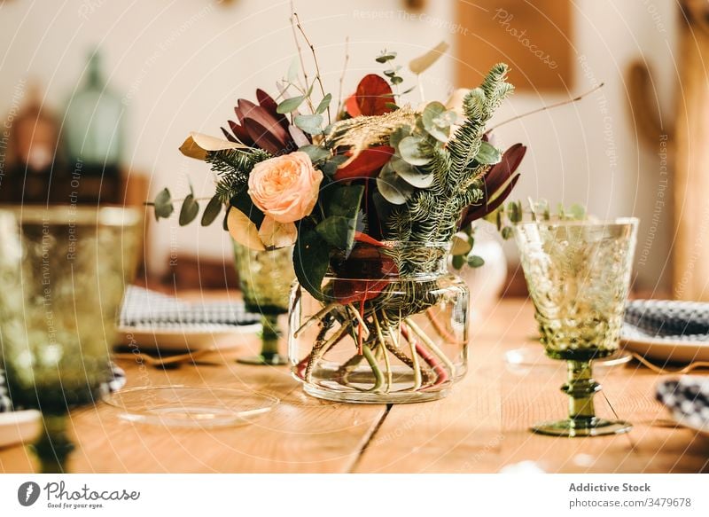 Blumen und Pflanzenzweige auf einer Vase, die einen Holztisch schmückt Haufen Blatt Blumenstrauß Wasser Blütenblatt Konzept Glas frisch Blütezeit Innenbereich