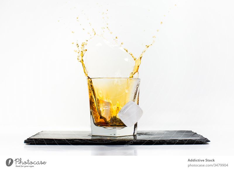 Eiswürfel fallen mit Getränk ins Glas trinken platschen gelb kalt liquide Würfel Schiefer frisch Erfrischung Moment durchsichtig Alkohol Cocktail Whiskey