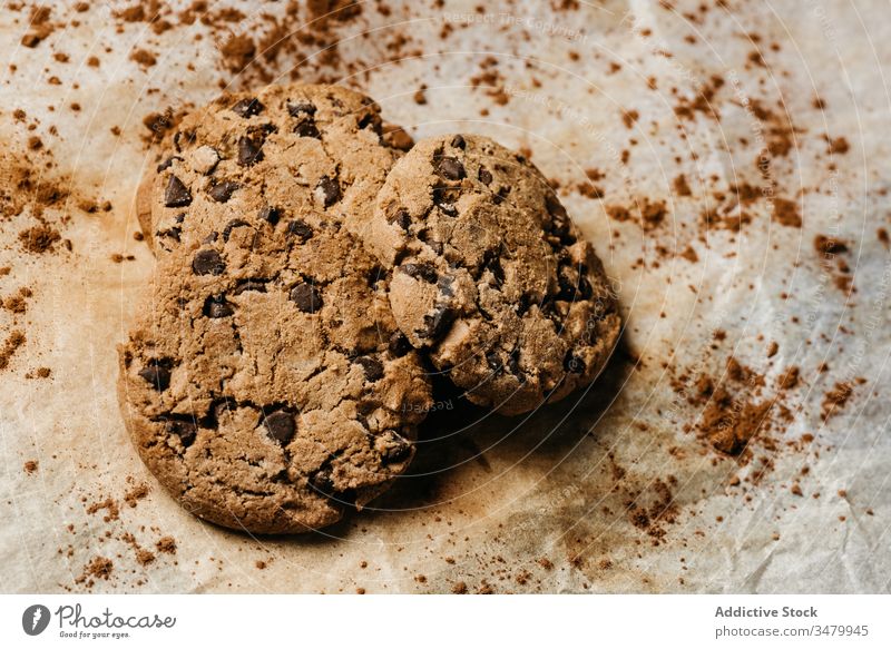 Leckere Schokoladenkekse auf Holztisch Keks hölzern gebacken Gebäck Biskuit süß Papier Lebensmittel Dessert dunkel geschmackvoll selbstgemacht Snack frisch