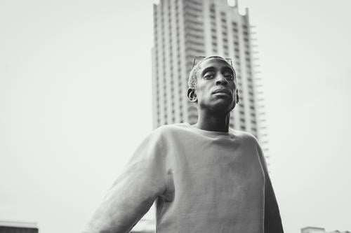 Trendiger afroamerikanischer Mann geht auf der Straße in der Stadt Stil Großstadt modern ethnisch unterirdisch Eingang selbstbewusst urban Outfit Lifestyle