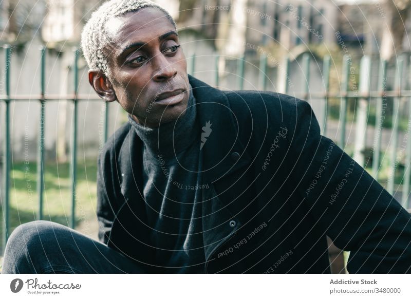 Trendiger afroamerikanischer Mann im Park Stil ruhen Großstadt ausrichten Jacke ethnisch urban modern männlich Lifestyle lässig trendy ernst selbstbewusst