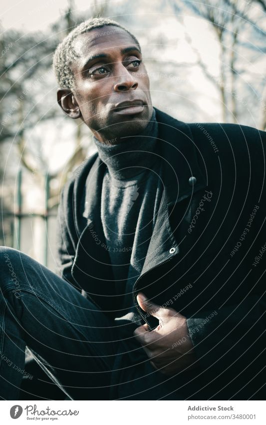 Trendiger afroamerikanischer Mann im Park Stil ruhen Großstadt ausrichten Jacke ethnisch urban modern männlich Lifestyle lässig trendy ernst selbstbewusst