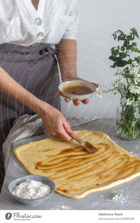 Nutzpflanzenfrau beim Aufspießen von Apfelmus auf Teig Frau Teigwaren Schliere Püree Gebäck Koch Tisch Mehl Blume Blumenstrauß Schürze Küche vorbereiten