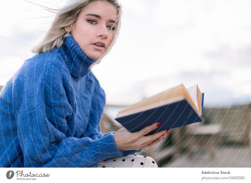 Junge Frau liest Buch an der Meeresküste Terrasse MEER Bank Strand ruhen lesen jung blau Pullover Natur sich[Akk] entspannen hölzern Stil Urlaub genießen
