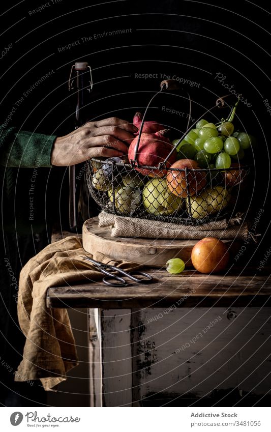 Ältere Person, die Obst aus dem Korb nimmt Frucht Apfel Trauben rustikal Tisch pflücken frisch Lebensmittel organisch natürlich reif Vitamin Gesundheit