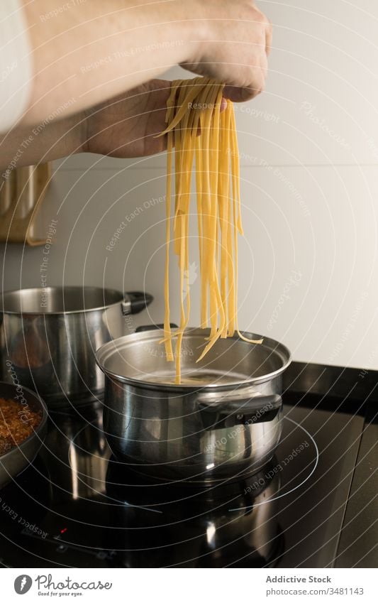 Koch, der die Spaghetti mit kochendem Wasser in die Pfanne gibt Spätzle vorbereiten Nudel Kochtopf setzen Hand selbstgemacht Küche Lebensmittel kulinarisch